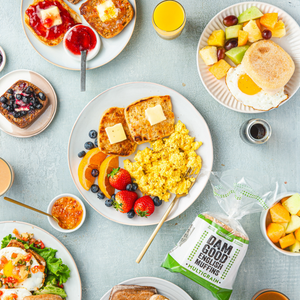 Assorted breakfast items including eggs, Dam Good English Muffins, fruit, and muffins on a light blue tablecloth.
