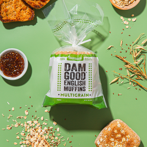 Packaged multigrain Dam Good English Muffins with ingredients on a green background