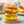 Stacked English muffin breakfast sandwiches with egg and avocado on a plate with a blurred background