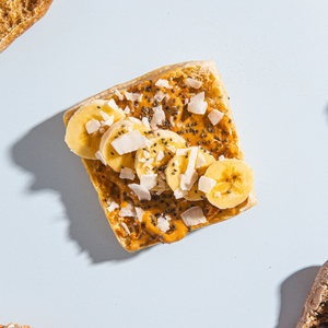 Sourdough Dam Good English Muffin Whole Wheat Toast with banana slices and coconut flakes on a light blue background