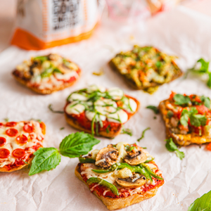 Small Dam Good English Muffin pizzas with various toppings on a white surface